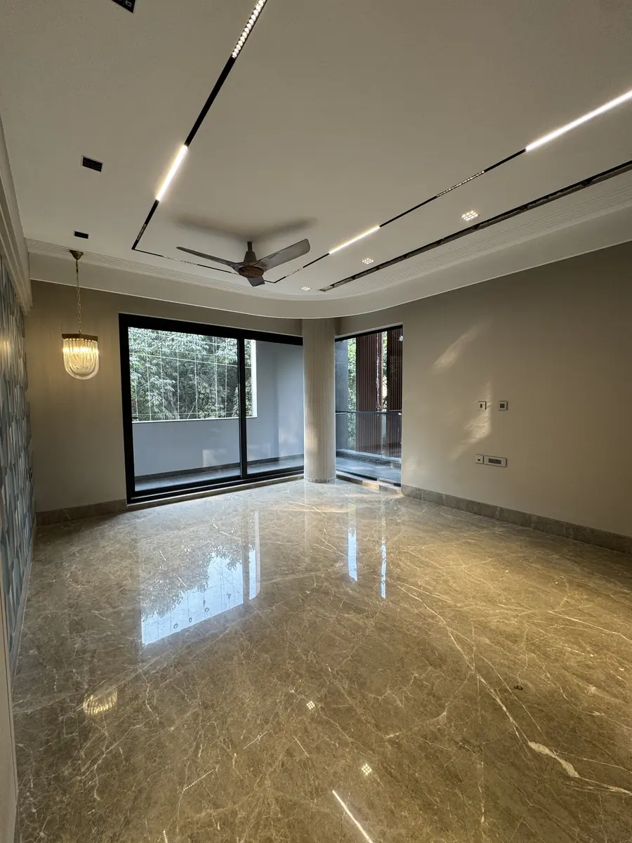 Living room with full-height glazing and a fluted column in a luxury builder floor in Gurgaon